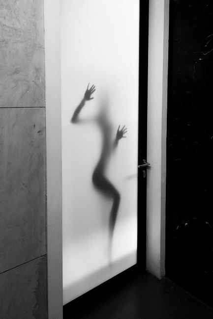 Силуэт женщины просвечивается через стеклянную дверь